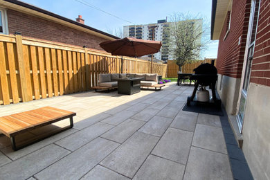 Patio - large modern backyard stone patio idea in Toronto with no cover