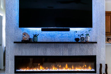タンパにあるお手頃価格の中くらいなラスティックスタイルのおしゃれなLDK (白い壁、濃色無垢フローリング、横長型暖炉、タイルの暖炉まわり、壁掛け型テレビ、茶色い床) の写真