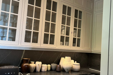 Diseño de cocina tradicional con despensa, armarios tipo vitrina, puertas de armario blancas, encimera de granito, salpicadero negro, puertas de granito y encimeras negras