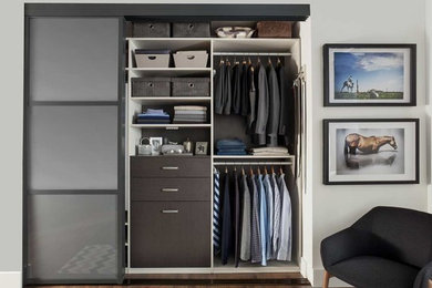 Diseño de armario de hombre minimalista de tamaño medio con suelo de madera oscura y puertas de armario de madera en tonos medios