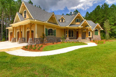Example of a large arts and crafts yellow two-story stone gable roof design in Atlanta