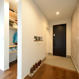 他の地域の片開きドアラスティックスタイルのおしゃれな玄関ホール (マルチカラーの壁、無垢フローリング、黒いドア、茶色い床) の写真