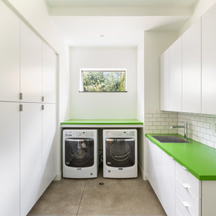 Contemporary u-shaped separated utility room in Denver with green worktops, flat-panel cabinets, white cabinets, white walls, concrete flooring, a side by side washer and dryer, grey floors, a submerged sink and laminate countertops.