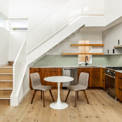 Open concept kitchen - mid-sized 1960s l-shaped light wood floor open concept kitchen idea in Seattle with an undermount sink, flat-panel cabinets, brown cabinets, quartz countertops, white backsplash, ceramic backsplash, stainless steel appliances, no island and white countertops