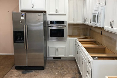 This is an example of a large transitional l-shaped separate kitchen in Wichita with raised-panel cabinets, white cabinets, stainless steel appliances and no island.