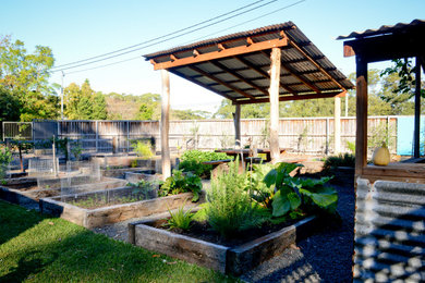 Modelo de jardín de estilo de casa de campo grande en primavera en patio trasero con huerto, exposición parcial al sol, gravilla y con madera