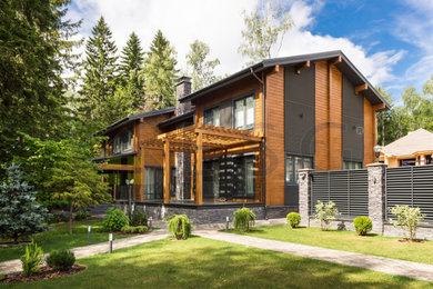 Идея дизайна: большой, двухэтажный, деревянный, коричневый частный загородный дом в современном стиле с двускатной крышей и серой крышей