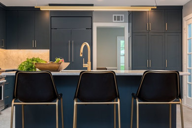 Open concept kitchen - mid-sized transitional l-shaped laminate floor and multicolored floor open concept kitchen idea in Milwaukee with a single-bowl sink, shaker cabinets, gray cabinets, granite countertops, gray backsplash, stone slab backsplash, paneled appliances and an island