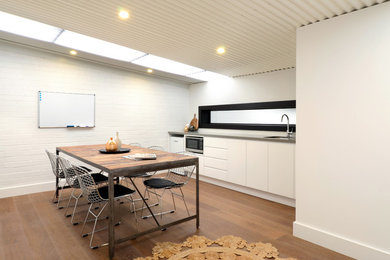 Design ideas for a mid-sized modern single-wall eat-in kitchen in Wollongong with a single-bowl sink, flat-panel cabinets, quartz benchtops, white splashback, stainless steel appliances, medium hardwood floors and no island.