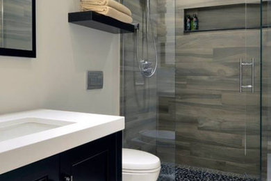 Inspiration for a mid-sized contemporary 3/4 black tile, brown tile, gray tile and porcelain tile porcelain tile and white floor alcove shower remodel in Orange County with recessed-panel cabinets, black cabinets, a wall-mount toilet, beige walls, an undermount sink, solid surface countertops and a hinged shower door