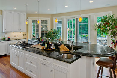 Inspiration for a large timeless u-shaped medium tone wood floor eat-in kitchen remodel in Other with a drop-in sink, beaded inset cabinets, white cabinets, marble countertops, white backsplash, ceramic backsplash, stainless steel appliances and an island