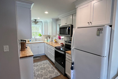 Example of a small transitional u-shaped vinyl floor and brown floor eat-in kitchen design in Detroit with a drop-in sink, shaker cabinets, white cabinets, wood countertops, white backsplash, marble backsplash, stainless steel appliances, no island and beige countertops