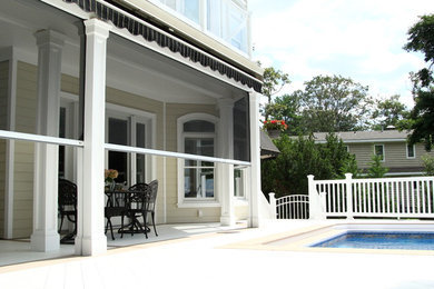 Large beach style screened-in back porch idea in New York with decking and a roof extension