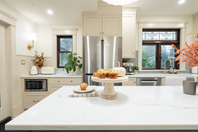 Kitchen - mid-sized traditional porcelain tile and beige floor kitchen idea in Vancouver with a farmhouse sink, shaker cabinets, beige cabinets, quartz countertops, blue backsplash, ceramic backsplash and an island