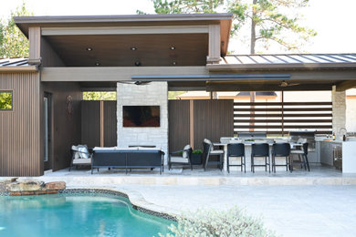Large minimalist backyard stone patio kitchen photo in Houston with a roof extension