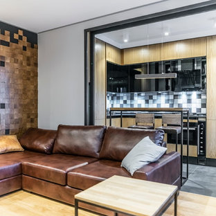 Пример оригинального дизайна интерьера: угловая кухня-гостиная в современном стиле с плоскими фасадами, фасадами цвета дерева среднего тона, разноцветным фартуком и черной техникой без острова