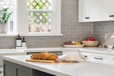 Open concept kitchen - mid-sized craftsman u-shaped porcelain tile and gray floor open concept kitchen idea in San Diego with a farmhouse sink, shaker cabinets, white cabinets, quartz countertops, gray backsplash, ceramic backsplash, stainless steel appliances, an island and white countertops