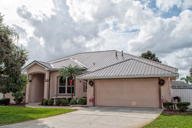 Photo of a large traditional one-storey stucco house exterior in Orlando with a hip roof and a metal roof.