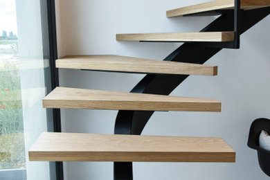 Idées déco pour un très grand escalier contemporain en L avec des marches en bois et un garde-corps en métal.