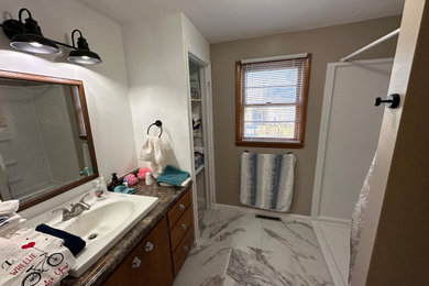 Mid-sized 3/4 porcelain tile, white floor and single-sink bathroom photo in Other with flat-panel cabinets, dark wood cabinets, a two-piece toilet, brown walls, a drop-in sink, laminate countertops, brown countertops and a built-in vanity