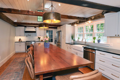 Inspiration for a huge country l-shaped medium tone wood floor, brown floor and shiplap ceiling eat-in kitchen remodel in Boston with a farmhouse sink, shaker cabinets, white cabinets, soapstone countertops, stainless steel appliances, an island and black countertops
