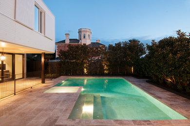 This is an example of a mid-sized modern backyard custom-shaped pool in Melbourne with natural stone pavers.