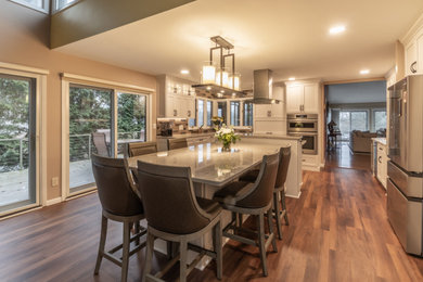 Example of a mid-sized transitional u-shaped medium tone wood floor and brown floor eat-in kitchen design in Cleveland with a drop-in sink, shaker cabinets, white cabinets, quartzite countertops, multicolored backsplash, ceramic backsplash, stainless steel appliances, an island and gray countertops