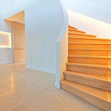 Viertelgewendelte Betontreppe mit Stufen in Eiche und geschwungener Innenwand