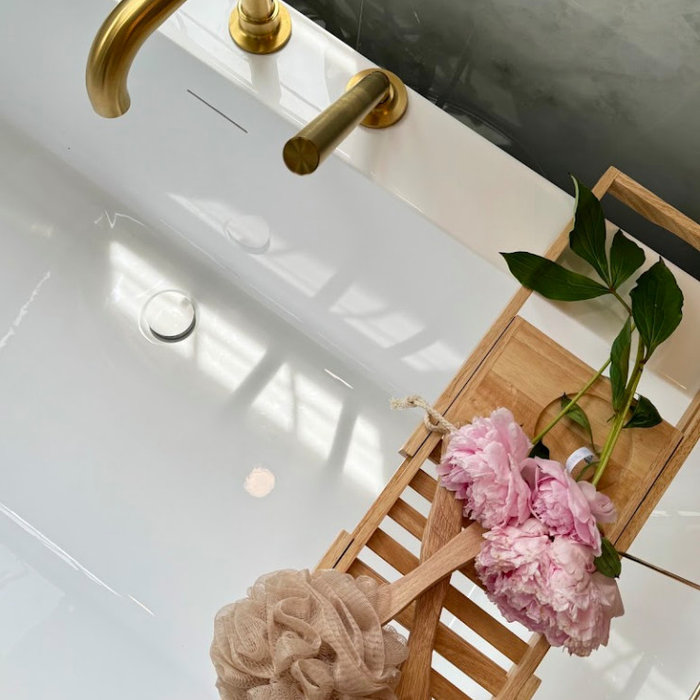Organic Modern bathroom design in Rockville, MD featuring a spa-like atmosphere with large-format porcelain tile, natural wood vanities, and minimalist black hardware. This primary bath renovation by