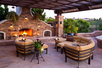 Photo of a mid-sized mediterranean backyard patio in Los Angeles with a fire feature, a pergola and natural stone pavers.