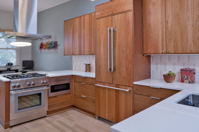 Example of a mid-sized mid-century modern u-shaped light wood floor, beige floor and vaulted ceiling open concept kitchen design in DC Metro with an undermount sink, flat-panel cabinets, medium tone wood cabinets, quartz countertops, white backsplash, ceramic backsplash, paneled appliances, a peninsula and white countertops