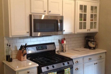 Enclosed kitchen - small traditional galley ceramic tile enclosed kitchen idea in Indianapolis with a farmhouse sink, recessed-panel cabinets, white cabinets, quartzite countertops, white backsplash, ceramic backsplash and stainless steel appliances