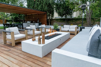 Outdoor kitchen deck - large modern backyard outdoor kitchen deck idea in Los Angeles with a pergola