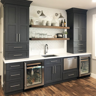 Imagen de sótano con puerta clásico renovado, de tamaño medio, con paredes grises, suelo laminado, chimenea tradicional, marco de chimenea de piedra y suelo marrón