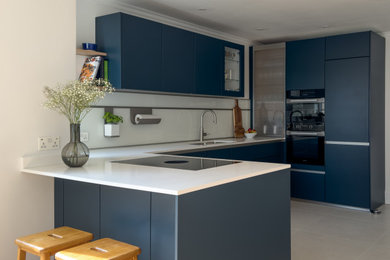 Example of a mid-sized trendy u-shaped eat-in kitchen design in Other with an integrated sink, flat-panel cabinets, blue cabinets, quartzite countertops, white backsplash, glass sheet backsplash, black appliances and white countertops