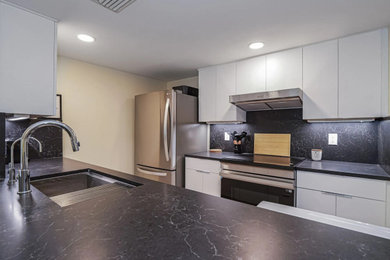 Eat-in kitchen - small modern galley vinyl floor and beige floor eat-in kitchen idea in Miami with an undermount sink, flat-panel cabinets, white cabinets, quartz countertops, black backsplash, quartz backsplash, stainless steel appliances, a peninsula and black countertops