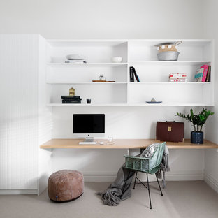 Photo of a mid-sized contemporary home office in Melbourne with white walls, carpet, a built-in desk, beige floor and a library.