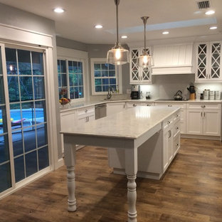 Contemporary kitchen pantry designs - Example of a trendy u-shaped medium tone wood floor and brown floor kitchen pantry design in Jacksonville with a single-bowl sink, flat-panel cabinets, white cabinets, white backsplash, stainless steel appliances and an island