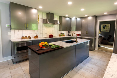 Example of a large trendy galley vinyl floor and beige floor kitchen design in Atlanta with an undermount sink, flat-panel cabinets, gray cabinets, quartz countertops, white backsplash, porcelain backsplash, stainless steel appliances, an island and beige countertops