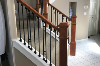 ポートランドにあるラグジュアリーな広いコンテンポラリースタイルのおしゃれなかね折れ階段 (カーペット張りの蹴込み板、木材の手すり) の写真