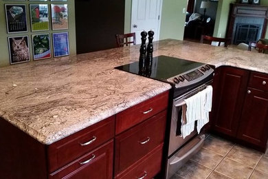 Example of a mid-sized classic l-shaped ceramic tile and gray floor open concept kitchen design in Portland Maine with an undermount sink, raised-panel cabinets, dark wood cabinets, granite countertops, stainless steel appliances and an island