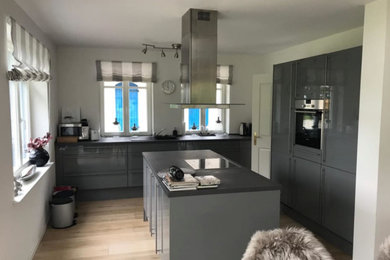 Offene, Einzeilige Landhausstil Küche mit Einbauwaschbecken, grauen Schränken, Betonarbeitsplatte, Küchenrückwand in Grau, Küchengeräten aus Edelstahl, hellem Holzboden, Kücheninsel, braunem Boden und grauer Arbeitsplatte in Hamburg