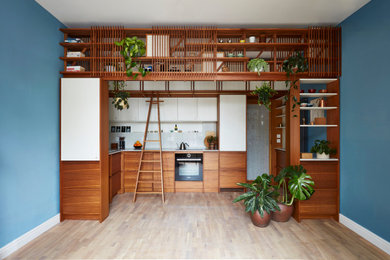 This is an example of a small scandi single-wall kitchen/diner in Other with a single-bowl sink, flat-panel cabinets, medium wood cabinets, quartz worktops, grey splashback, engineered quartz splashback, integrated appliances, light hardwood flooring, no island, beige floors, grey worktops and a feature wall.
