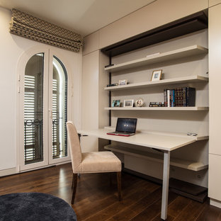 Small modern study in Tel Aviv with beige walls, travertine flooring, a built-in desk and beige floors.