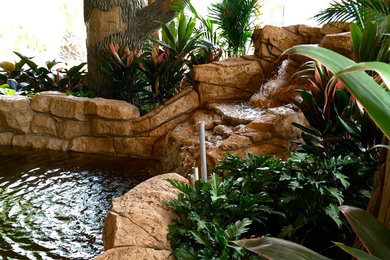 Inspiration for a mid-sized tropical backyard custom-shaped lap pool in Orlando with a water feature and natural stone pavers.