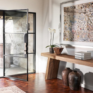 Immagine di un ingresso moderno di medie dimensioni con pareti bianche, pavimento marrone, una porta singola e una porta in vetro