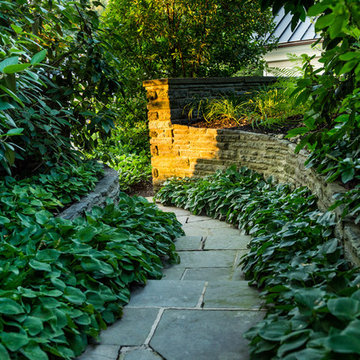 A stone stepped pathway is lined with lush, green plantings