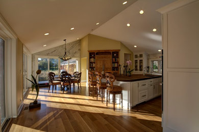 Example of a large l-shaped light wood floor kitchen design in Chicago with an island, an undermount sink, white cabinets, white backsplash and stone slab backsplash