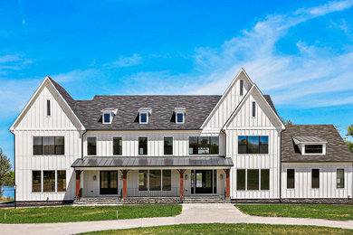 Example of a huge cottage white three-story house exterior design in DC Metro with a gray roof