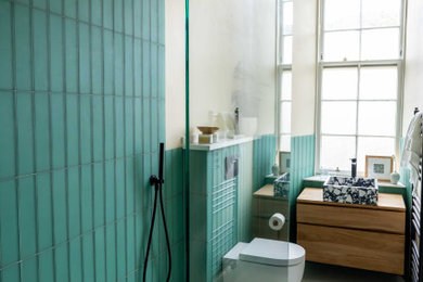 This is an example of a medium sized contemporary bathroom in Glasgow with a wall mounted toilet, green tiles, glass tiles, ceramic flooring, a wall-mounted sink, an open shower, a single sink, a floating vanity unit and a drop ceiling.